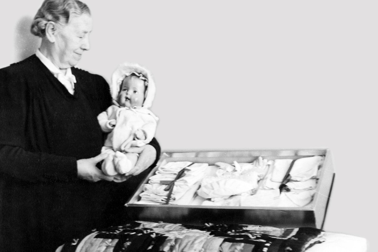 Helsingin ensikodin puheenjohtaja Miina Sillanpää esittelee äitiyspakkausta 2.6.1942 Helsingissä. Kuva: Työväen arkisto