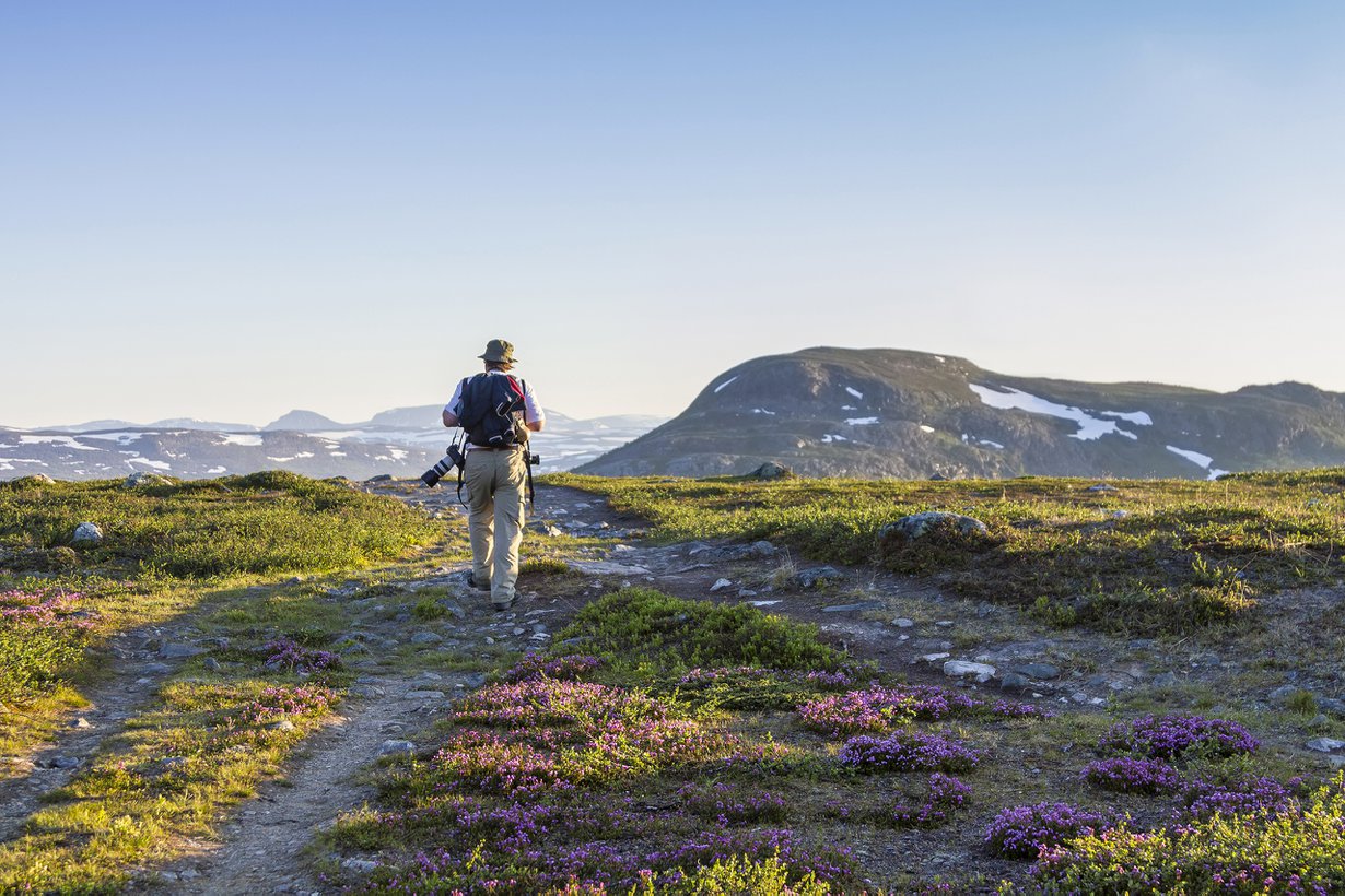 Kilpisjärven kesäyössä vaeltaja näkee tunturien lumilaikut ja polun kivet.
