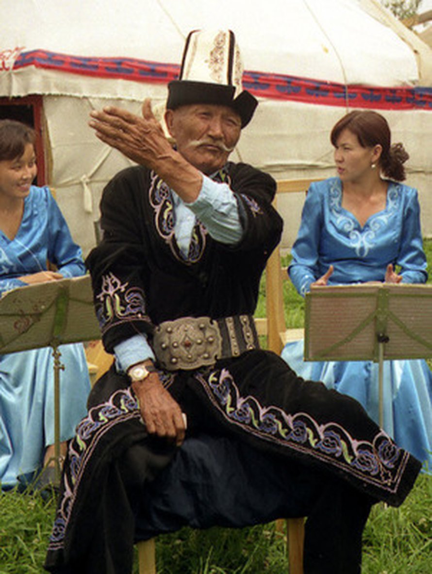 Kirgiisi muistelemassa kansallista legendaa. Kuva: <span class="photographer"><A HREF=http://en.wikipedia.org/wiki/File:Kyrgyz_Manaschi,_Karakol.jpg>Wikimedia Commons</A>.</span>