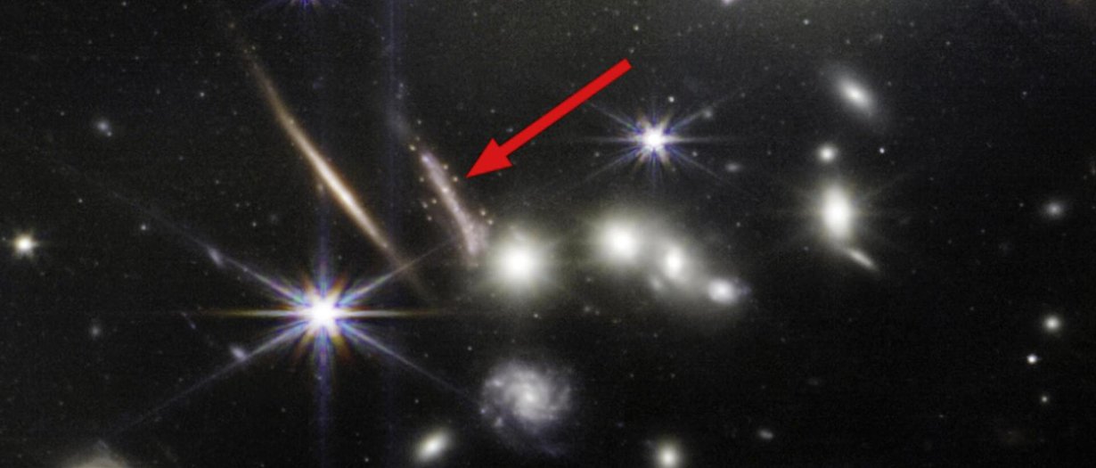Suurennos avaruusteleskooppi James Webbin isosta syvän avaruuden kuvasta heinäkuulta. Nuolella merkitystä kaaresta löytyi kiinnostavia ikivanhoja tähtijoukkoja. Kuva: NASA, ESA, CSA, STScI